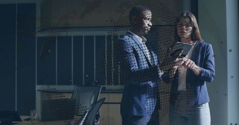 Business colleagues reviewing tablet in glass boardroom with reflections, collaboration