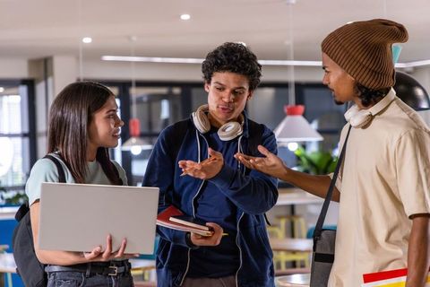 Diverse college students collaborating on group project with laptop and notebooks