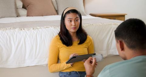 Couple Discussing Finances at Home Woman Holding Tablet While Partner Showing Card