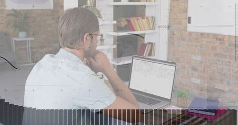 Man analyzing financial data on laptop in home office setting