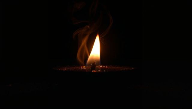Flickering Candle Flame with Smoke in Dark Room