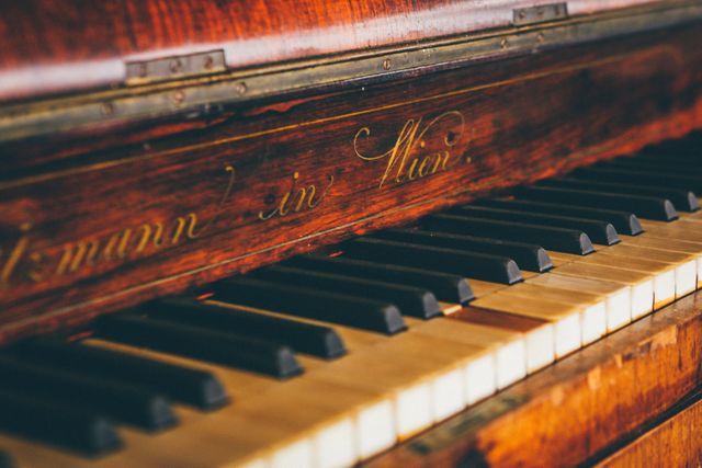 Close-up view of vintage piano keys with an ornate wood frame, showing signs of age and character. Ideal for footage in historical documentaries, music-related materials, antique promotions, or adding a nostalgic or classic ambiance to creative projects.