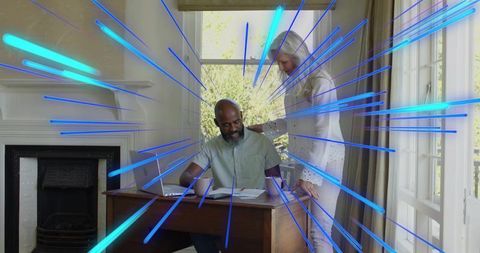 Couple reviewing bills at home desk with laptop, sunlight and blue digital motion streaks