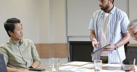 Diverse Team Discussing Insights with Tablet in Meeting Room
