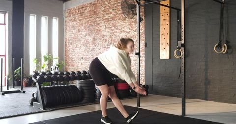 Woman Performing Dynamic Warm-up in Industrial Warehouse Gym