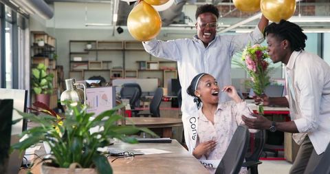 Celebrating Success in Modern Office with Balloons and Flowers