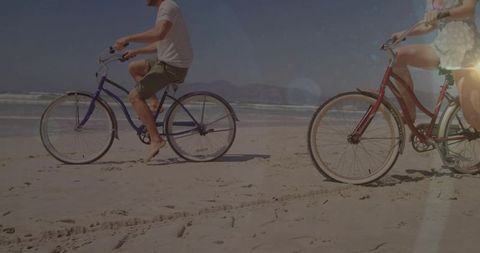 Couple riding bikes on a sunny beach day