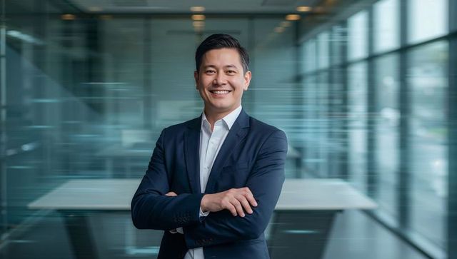 Confident asian executive standing arms crossed smiling in modern glass office
