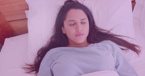 Peaceful Woman Relaxing on Bed with White Pillow and Wooden Headboard