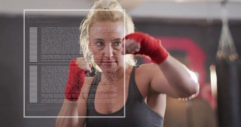 Female boxer throwing powerful jab in boxing gym wearing red wraps, focused training