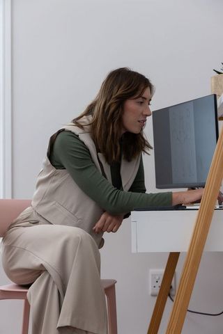 Woman leaning and typing at modern home desk in minimalist workspace focusing on productivity