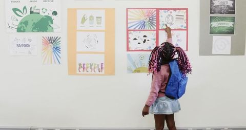 Young Girl Engaging with Recycling Posters in Classroom