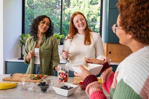 Diverse Women Collaborating on Fresh Fruit Preparations in Contemporary Kitchen
