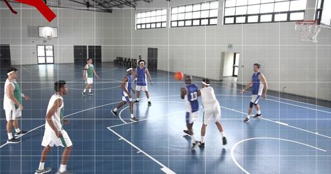Player driving past defender on indoor blue court during competitive basketball game, teamwork