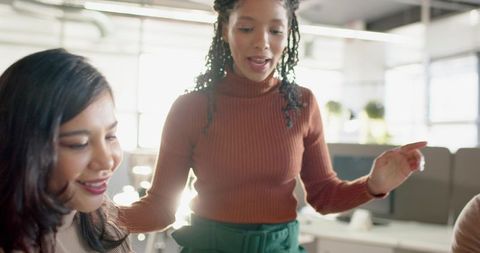 Collaborative Female Team in Bright Open-Plan Office Wearing Rust Ribbed Turtleneck