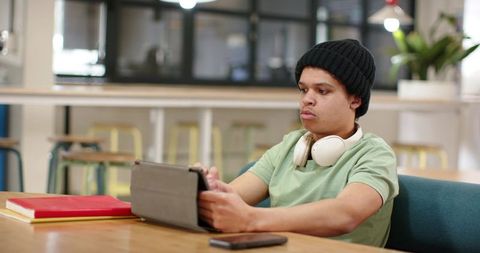 Young african american student studying with tablet and headphones in coworking hub