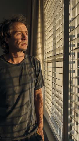 Man closing eyes while warm light filters blinds in contemplative vertical video