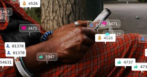 Man holding smartphone tapping screen with social overlays, red plaid beads closeup