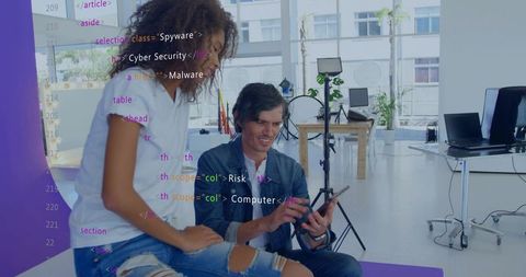 Coworkers reviewing code on tablet in studio workspace collaborating on cybersecurity