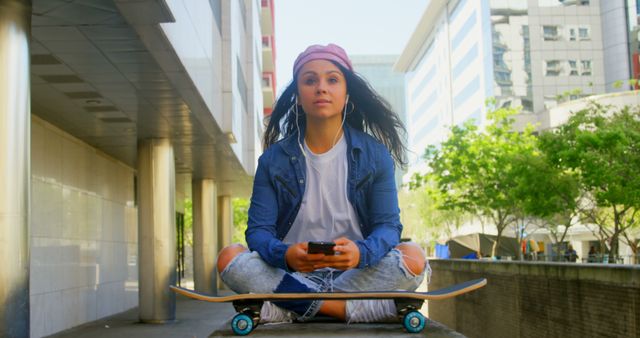 Urban young woman sitting on skateboard using smartphone - Download Free Stock Images Pikwizard.com