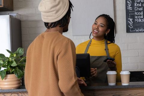 African american barista serving customer at cozy coffee shop counter, smiling
