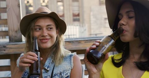 Caucasian and Biracial Women Enjoying Beer on Rooftop Celebration