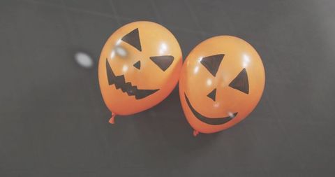 Two jack-o'-lantern balloons resting on dark fabric halloween decor flatlay