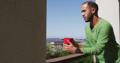 Man Relaxing on Balcony with Coffee enjoying Sun