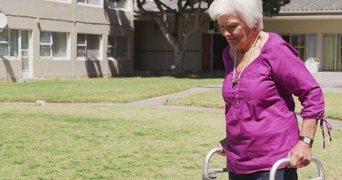 Senior woman using walker outdoors in assisted living
