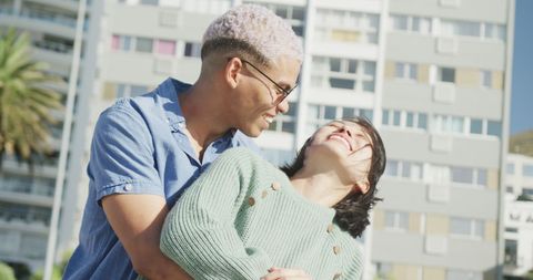 Diverse Couple Embracing and Laughing Outdoors on Sunny Day