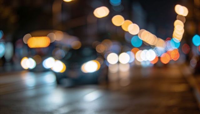 City night bokeh: glowing headlights and wet street reflections creating soft urban orbs