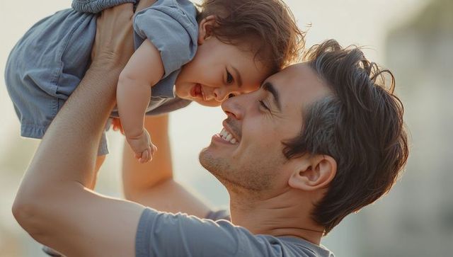 Father lifting smiling baby during golden hour bonding close-up parental warmth backlit