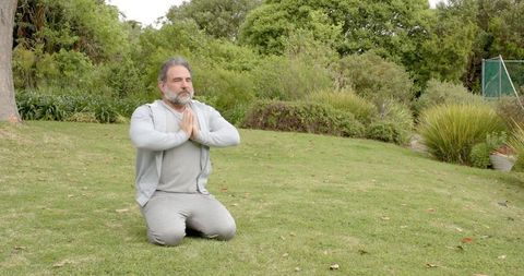 Mature Man Meditating in Lush Green Backyard