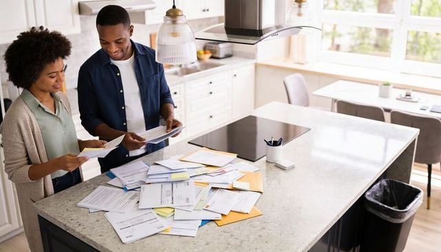 Couple reviewing household mail and bills on modern kitchen island, organizing finances