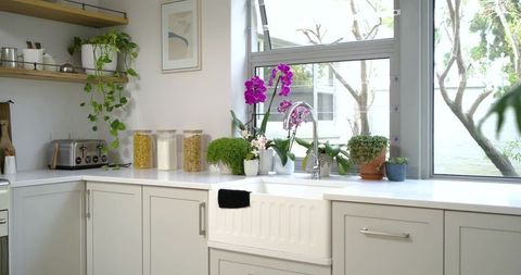 Bright minimalist kitchen countertop with apron sink, chrome faucet and purple orchids
