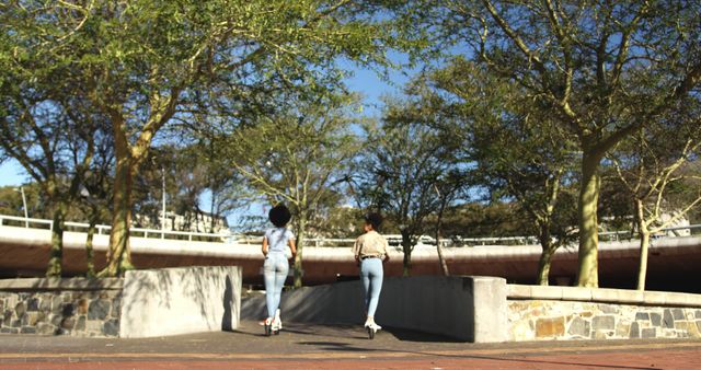 Two Women Walking in Urban Park on Sunny Day - Download Free Stock Images Pikwizard.com