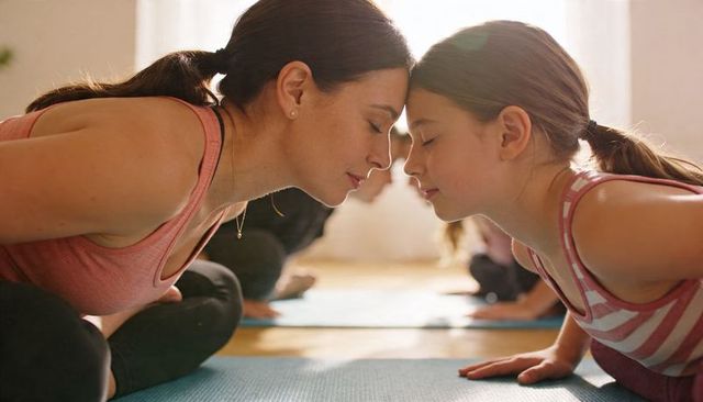 Mother and daughter touching foreheads during parent-child yoga practice