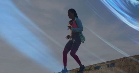 Dawn silhouette of athletic woman balancing on concrete ledge wearing running gear
