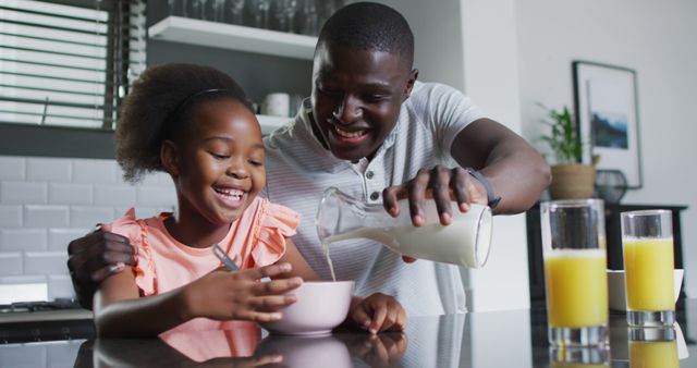 Image of african american father and daughter eating breakfast. Enjoying quality family time together at home.
