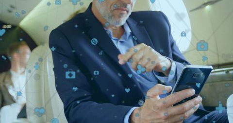 Businessman using smartphone on private jet with digital icons