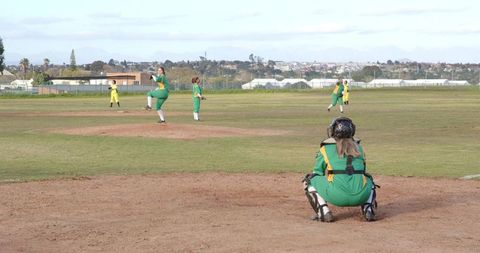 Female softball team in action with catcher in green uniform