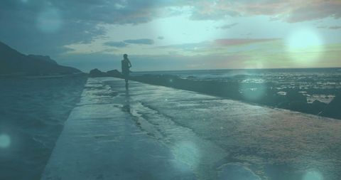 Silhouette of Jogger on Coastal Path at Sunrise with Artistic Light Flare