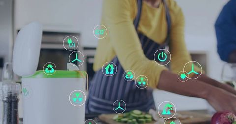 Man chopping cucumber on kitchen counter wearing apron and yellow top with composter eco icons