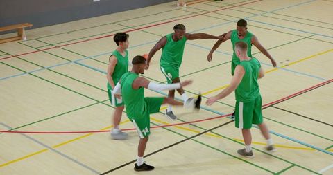 Diverse male basketball team practicing dynamic warmup and passing drills on indoor court