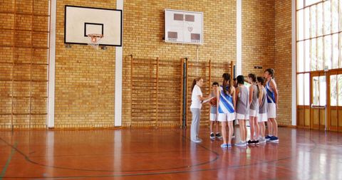 Coach giving strategy talk to youth basketball team in gymnasium