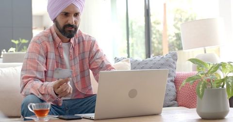 Man using credit card for online shopping on laptop at home