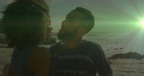 Romantic Couple Admiring Sunset on Rocky Shoreline with Lens Flare
