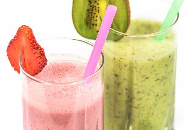 Two vibrant smoothies, one pink with a strawberry garnish and a green smoothie with a kiwi garnish. Ideal for use in health, fitness, and nutrition-themed designs and promotions. Suitable for recipe ideas, menus, or wellness advertisements emphasizing healthy and refreshing beverage options.