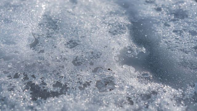 Glinting melting granular snow and broken ice crystals on winter path with sparkling frost