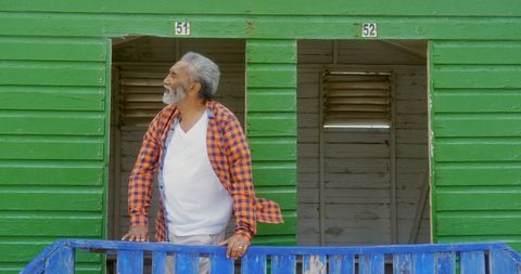 Senior Man Enjoying Sunny Day at Colorful Beach Hut